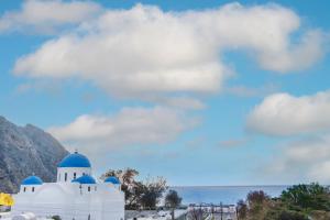 a white mosque with blue domes under a cloudy sky at SantoriniNY in Perissa