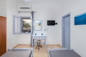 a room with two beds and a desk and a mirror at SantoriniNY in Perissa