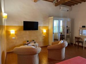 a living room with two chairs and a flat screen tv at Villa Terme Di Caldana B&B in Venturina Terme