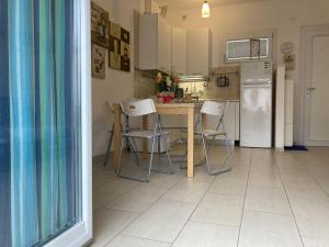 een keuken met een tafel, stoelen en een koelkast bij Romea in Rosolina Mare