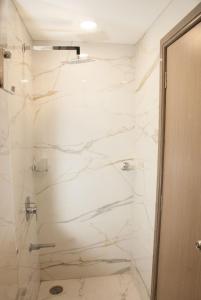 a bathroom with a shower with white marble walls at City Hotel in Mumbai