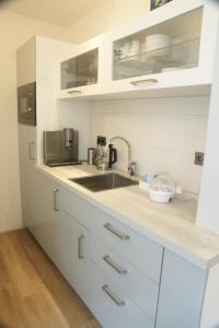 a kitchen with white cabinets and a sink at Texbed in Den Burg
