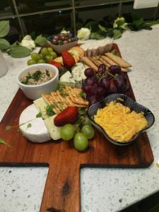 a wooden cutting board with different types of cheese and fruit at Sasavona Boutique Hotel in Polokwane