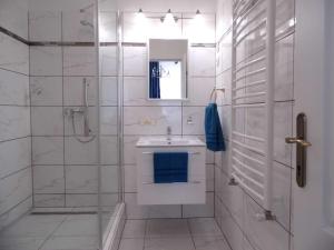 a white bathroom with a sink and a shower at Millennium Villa in Keszthely