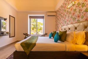 a bedroom with a large bed with yellow and blue pillows at juSTa Casa Frangipani Assagao Near Anjuna & Baga Beach in Old Goa
