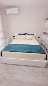 een slaapkamer met een bed met een blauwe deken en gordijnen bij Small Studio near the Olimpik Park in Tirana