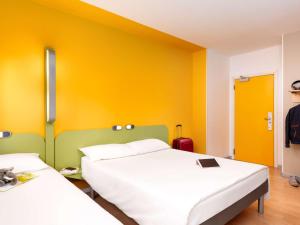 2 camas en una habitación con paredes amarillas en ibis budget Warszawa Centrum, en Varsovia