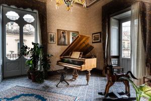 una stanza con pianoforte in una stanza con finestre di Palazzo Il Cavaliere B&B De Charme a Modica