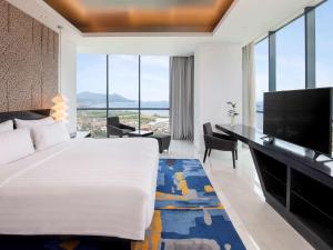 a hotel room with a large bed and a flat screen tv at Novotel Lampung in Bandar Lampung