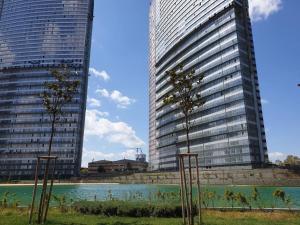 two tall buildings with trees in front of a body of water at Amazing Apartment in a vibrant Area with Stunning Lake View in Istanbul! in Esenyurt