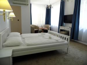 - une chambre avec un lit blanc et un salon dans l'établissement Millennium Villa, à Keszthely