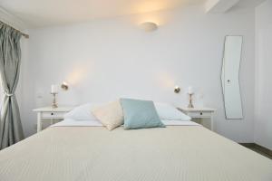 een slaapkamer met een wit bed, 2 tafels en een spiegel bij Room Annette in Dubrovnik