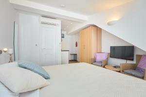 een witte slaapkamer met een bed en een televisie bij Room Annette in Dubrovnik