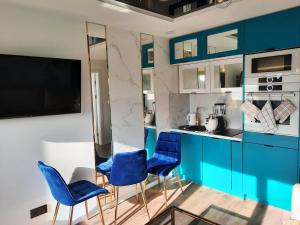 a kitchen with blue and white cabinets and blue chairs at Nadmorski Bursztyn in Rowy