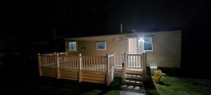 94 Newquay Bay Resort pet friendly في نيوكواي: كابينة خشبية صغيرة مع شرفة في الليل