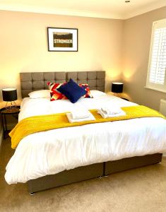 1 dormitorio con 1 cama grande y toallas. en NEW! Luxury YELLOW HOUSE Bright Modern Detatched Home with PRIVATE PARKING, NETFLIX Close Luton, M1, and AIRPORT Ideal for Families, Professionals, Consultants, LONGER STAY OPTIONS en Caddington