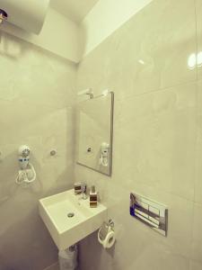 a white bathroom with a sink and a mirror at RiverSea Apartment Saranda in Sarandë