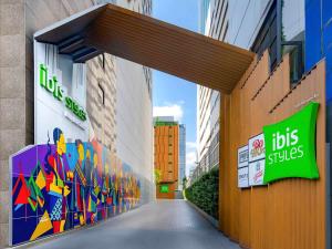 ibis Styles Bangkok Silom في بانكوك: ممر بين مبنيين طويلين مع علامات عليهم