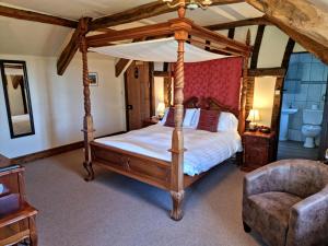 a bedroom with a four poster bed and a chair at Collaven Manor in Okehampton