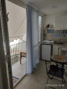 een keuken met een tafel en een balkon bij Deni's apartments per 2 con veranda balcone in Siracusa
