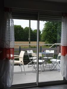 een patio met witte stoelen, een tafel en ramen bij Appartement de 2 chambres avec terrasse amenagee et wifi a Arnage in Arnage