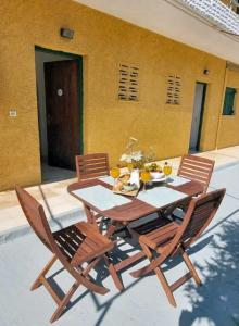 a wooden table and chairs with a table and a yellow building at Pagonia Apartments in Arillas