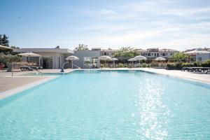 ein großer Swimmingpool mit Liegen und Sonnenschirmen in der Unterkunft Vada Village in Vada