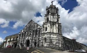 Una vieja iglesia con una cruz encima. en HOTEL HERENCIA 625 formerly Abaca Suites en Daraga