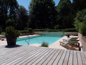 einen Pool neben einer Holzterrasse mit einem Stuhl in der Unterkunft Château Fleur D'Aya in Artigues-près-Bordeaux