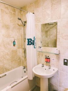 bagno con lavandino, vasca e tenda per la doccia di Boston West Hotel a Boston