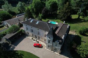 une vieille maison avec une voiture rouge garée devant elle dans l'établissement Château Fleur D'Aya, à Artigues-près-Bordeaux
