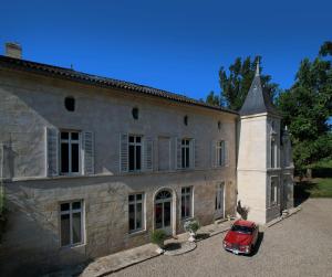 ein rotes Auto, das vor einem Gebäude parkt in der Unterkunft Château Fleur D'Aya in Artigues-près-Bordeaux