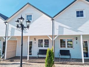 a white house with two benches on a porch at Domki Scandinavia in Rowy