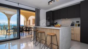 kuchnia z czarnymi szafkami i blatem z stołkami barowymi w obiekcie Contemporary loft style apartment with amazing sea views and with direct access to the beach from the community w Maladze