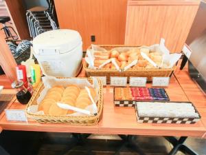 a table with baskets of bread and other foods at HOTEL LiVEMAX PREMIUM Himejieki-Minami in Himeji