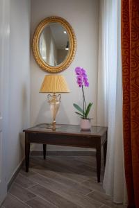 une table avec une lampe et un miroir mural dans l'établissement Saint Joseph, à Livourne