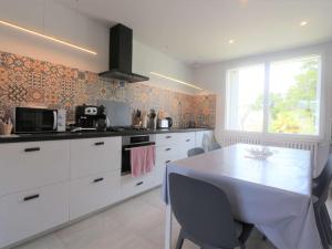 a kitchen with white cabinets and a table and a window at Maison rénovée 3 étoiles à 150m de la plage, idéale pour familles avec espace enfants et Wifi - FR-1-481-116 in Bénodet
