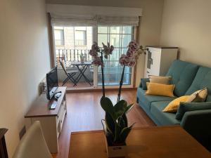 Una sala de estar con un sofá azul y una mesa. en Soños Sanxenxo, en Sanxenxo