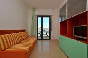a living room with a couch and a television at Residenza Verde in Lignano Sabbiadoro