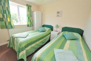 a bedroom with two beds and a window at Bridge House Apartment in Charmouth