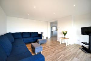 a living room with a blue couch and a tv at Yarrow in Charmouth