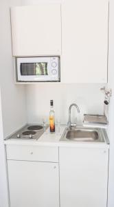 eine weiße Küche mit einer Spüle und einer Mikrowelle in der Unterkunft FoRest Međugorje in Međugorje
