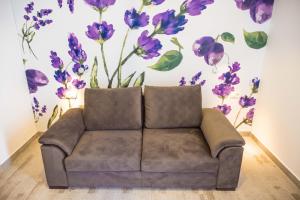 kanapa w pokoju z fioletowymi kwiatami na ścianie w obiekcie FoRest Međugorje w Medziugorie