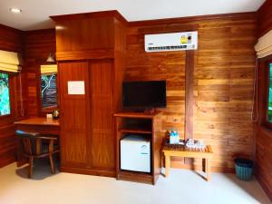 a room with wooden walls and a television and a desk at Tommy Resort in Haad Rin