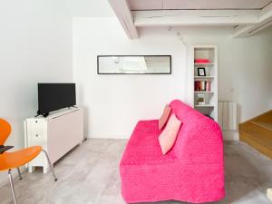 uma sala de estar com um sofá rosa e uma televisão em LE COCON D'AUTEUIL - ICI CONCIERGERIE em Auteuil