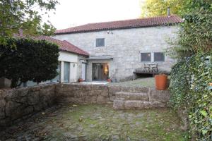 ein Steinhaus mit einer Steinmauer davor in der Unterkunft CASA RIO VEZ - Riverfront in Arcos de Valdevez