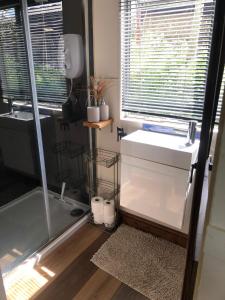 baño con lavabo, bañera y ventana en Cozy and peaceful cabin 15 mins from Lyme Regis, en Bridport