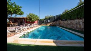 a large swimming pool with chairs and a wall at El Vergel in Cazorla
