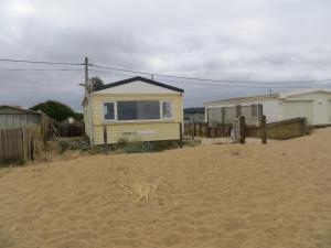 ヒーチャムにあるSunset Beach Retreatの砂浜の上に腰掛けた家