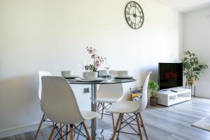 a dining room with a table and chairs and a clock at Ash View Place 3 -Heathrow - Thorpe Park - Free Parking in Staines